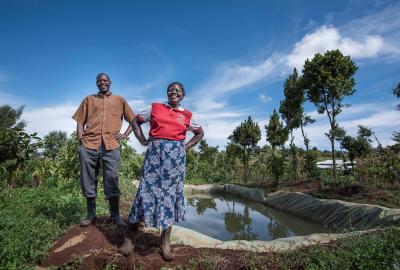 Man and woman standing and smiling on the soil of their farm